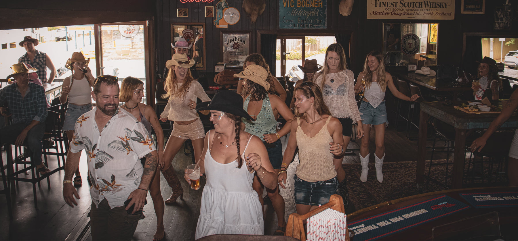Group of people dancing in a bar with various decorations and posters on the walls.